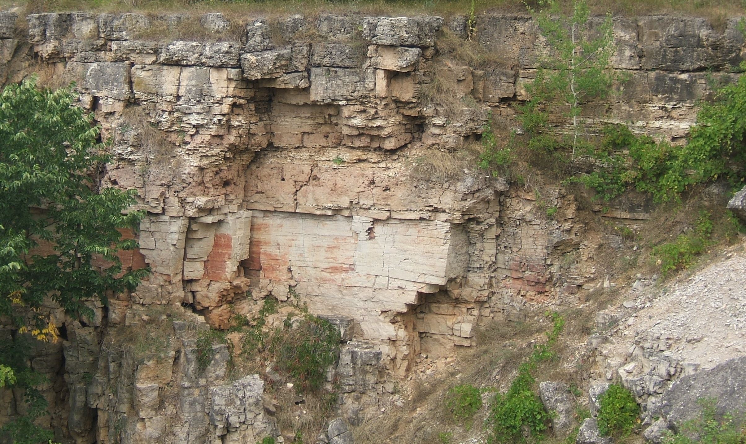A cliff face showing cracks and eroded gravel
